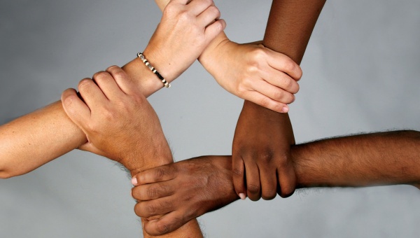 Braços de persones de diferents races units representant el respecte a la diversitat 